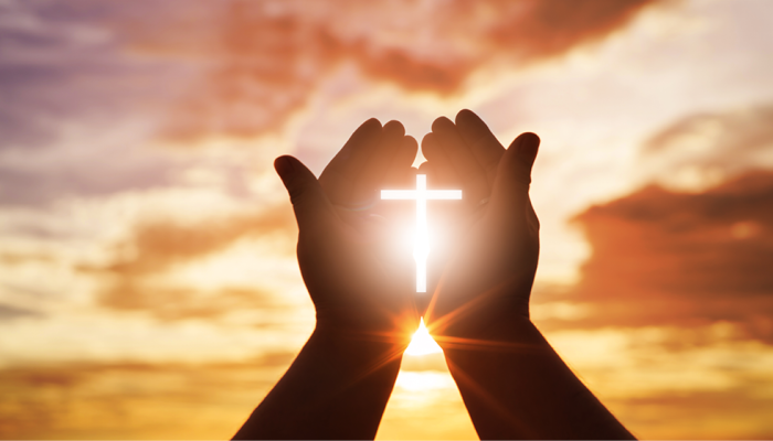 Hands holding a shining cross